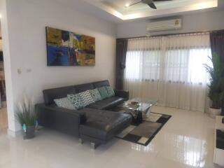 Modern living room with a black sofa, glass coffee table, and wall art