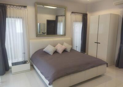 Modern bedroom with large bed, wardrobe, and curtains