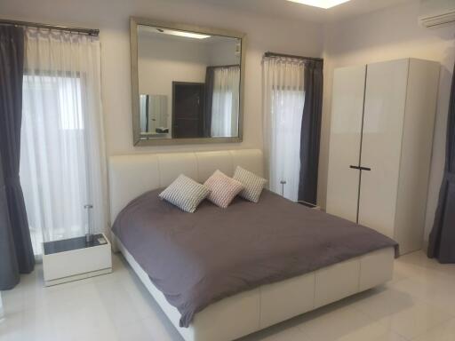 Modern bedroom with large bed, wardrobe, and curtains