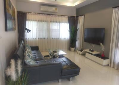 Modern living room with sectional sofa, TV, and air conditioning