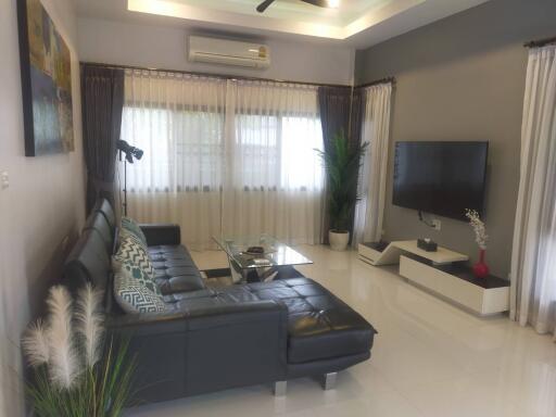 Modern living room with sectional sofa, TV, and air conditioning