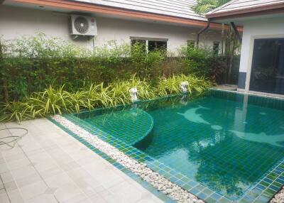 Well-maintained outdoor pool with green tiles and modern landscaping