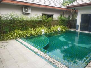 Well-maintained outdoor pool with green tiles and modern landscaping