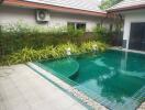 Well-maintained outdoor pool with green tiles and modern landscaping