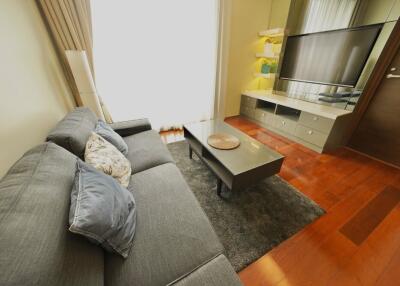 Modern living room with grey sofa, coffee table, TV, and wooden flooring