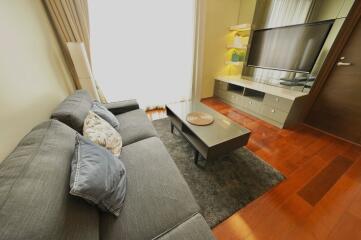 Modern living room with grey sofa, coffee table, TV, and wooden flooring