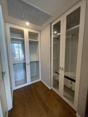 Spacious walk-in closet with wooden flooring and glass door cabinets