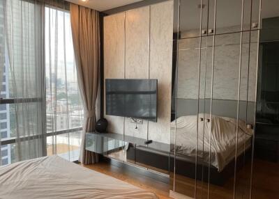 Modern bedroom with large floor-to-ceiling windows, TV mounted on the wall, and mirrored closet doors