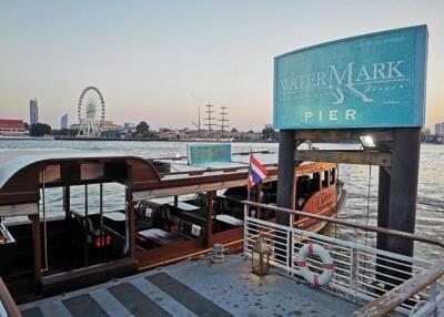 A pier with a boat docked and a large Ferris wheel in the background