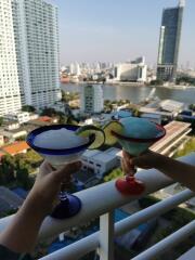 Two people holding drinks on a balcony with a city view