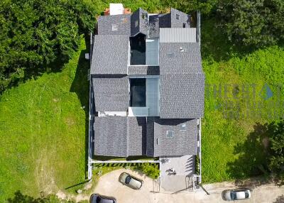 Aerial view of a large house with a gray roof and green surroundings