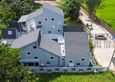 Aerial view of a multi-story residential building with a modern design, surrounded by greenery