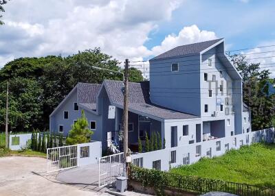 Modern blue-grey house with multiple pitched roofs and white fence