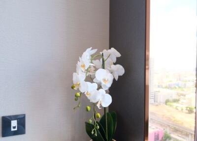 Decorative element with a flower vase and a decorative dish beside a window