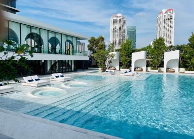 Luxurious outdoor swimming pool area with modern seating arrangements and high-rise buildings in the background