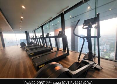 Modern fitness center with treadmills and elliptical machines in a high-rise building with city view