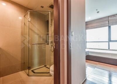 Modern bathroom with glass shower and adjacent bedroom with large windows