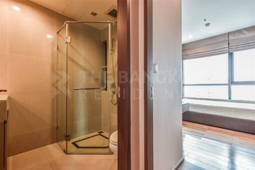 Modern bathroom with glass shower and adjacent bedroom with large windows