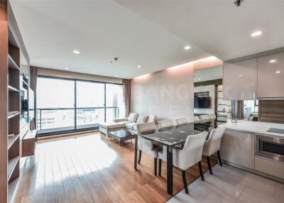 Spacious modern living room with a large window, comfortable seating, and an open kitchen