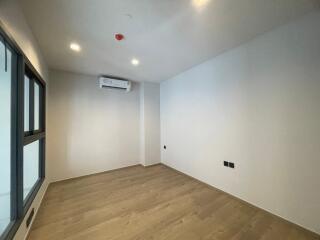 Spacious bedroom with wooden flooring and wall-mounted air conditioning.