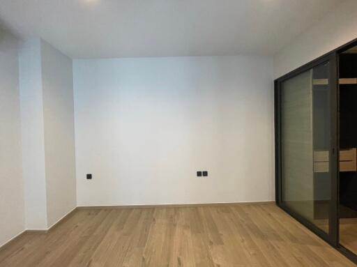 Empty bedroom with wooden flooring and glass sliding doors