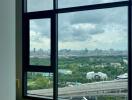 A bedroom with a large window offering a scenic city view