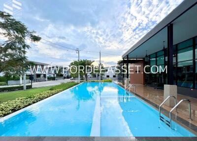 Modern swimming pool area with adjacent building and lush greenery