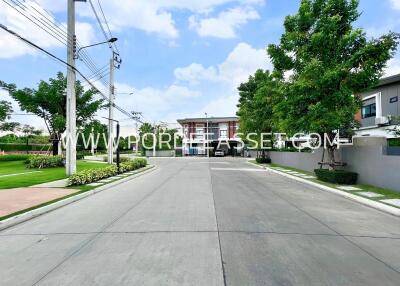 Residential community entrance with greenery and modern houses