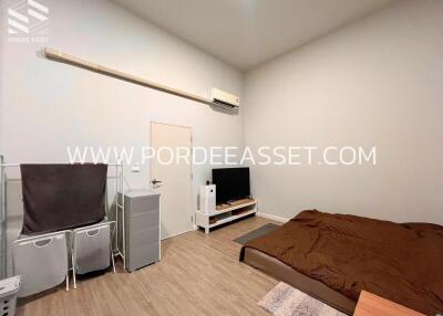 Spacious bedroom with a queen-size bed, wall-mounted air conditioner, TV unit, and storage baskets.