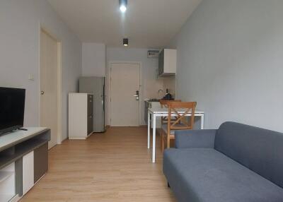 Living room with a couch, dining area, and a kitchen in the background