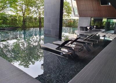 Luxury outdoor pool area with sun loungers and lush greenery