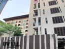 Exterior view of a modern condominium building with entrance and sign