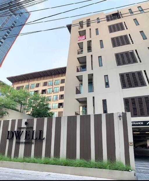 Exterior view of a modern condominium building with entrance and sign