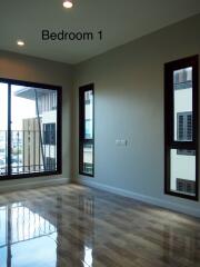 Modern bedroom with polished wooden floor and large windows labeled Bedroom 1