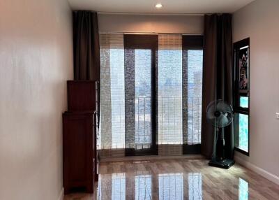 Living room with large windows and curtains, wooden cabinet, and floor fan