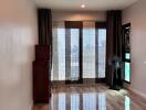 Living room with large windows and curtains, wooden cabinet, and floor fan