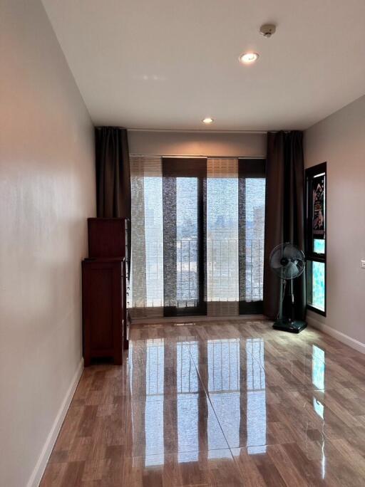 Living room with large windows and curtains, wooden cabinet, and floor fan