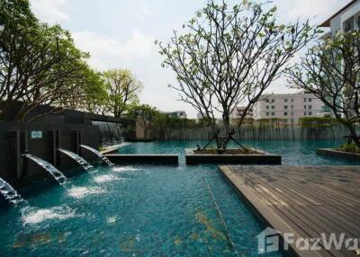 Outdoor swimming pool area with water features and surrounding greenery