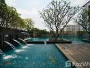 Outdoor swimming pool area with water features and surrounding greenery