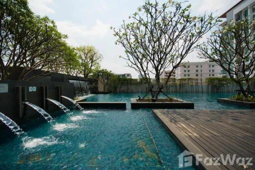 Outdoor swimming pool area with water features and surrounding greenery