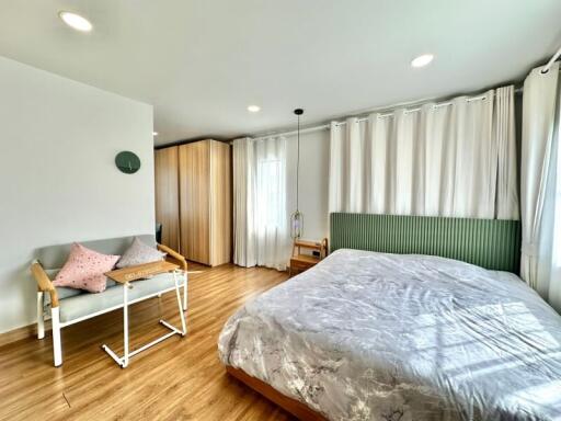 Spacious bedroom with wooden flooring, large bed, and sitting area