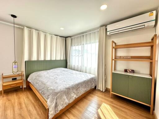 Modern bedroom with wooden flooring and green-themed decor