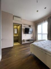 Bedroom with wooden flooring, large window, mounted TV, and attached bathroom