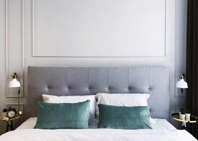 Modern bedroom with gray tufted headboard and green accent pillows