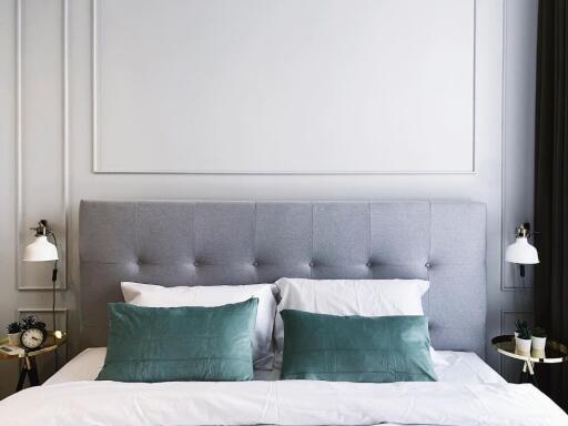 Modern bedroom with gray tufted headboard and green accent pillows