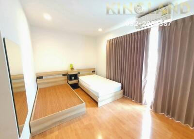 Bright and spacious bedroom with wooden flooring, large window, and ample storage space