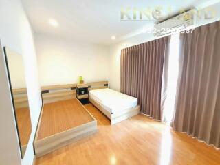 Bright and spacious bedroom with wooden flooring, large window, and ample storage space