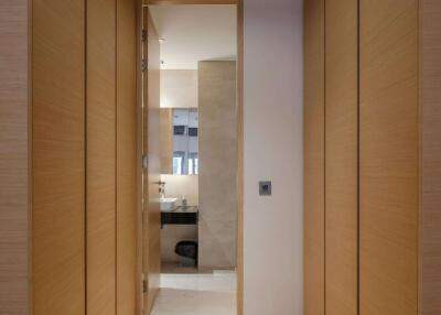 Hallway leading to bathroom with wood panel walls