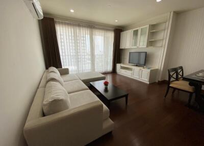 Living room with a white sectional sofa, coffee table, TV, and dining area