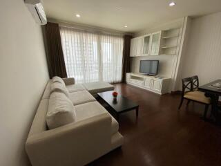 Living room with a white sectional sofa, coffee table, TV, and dining area